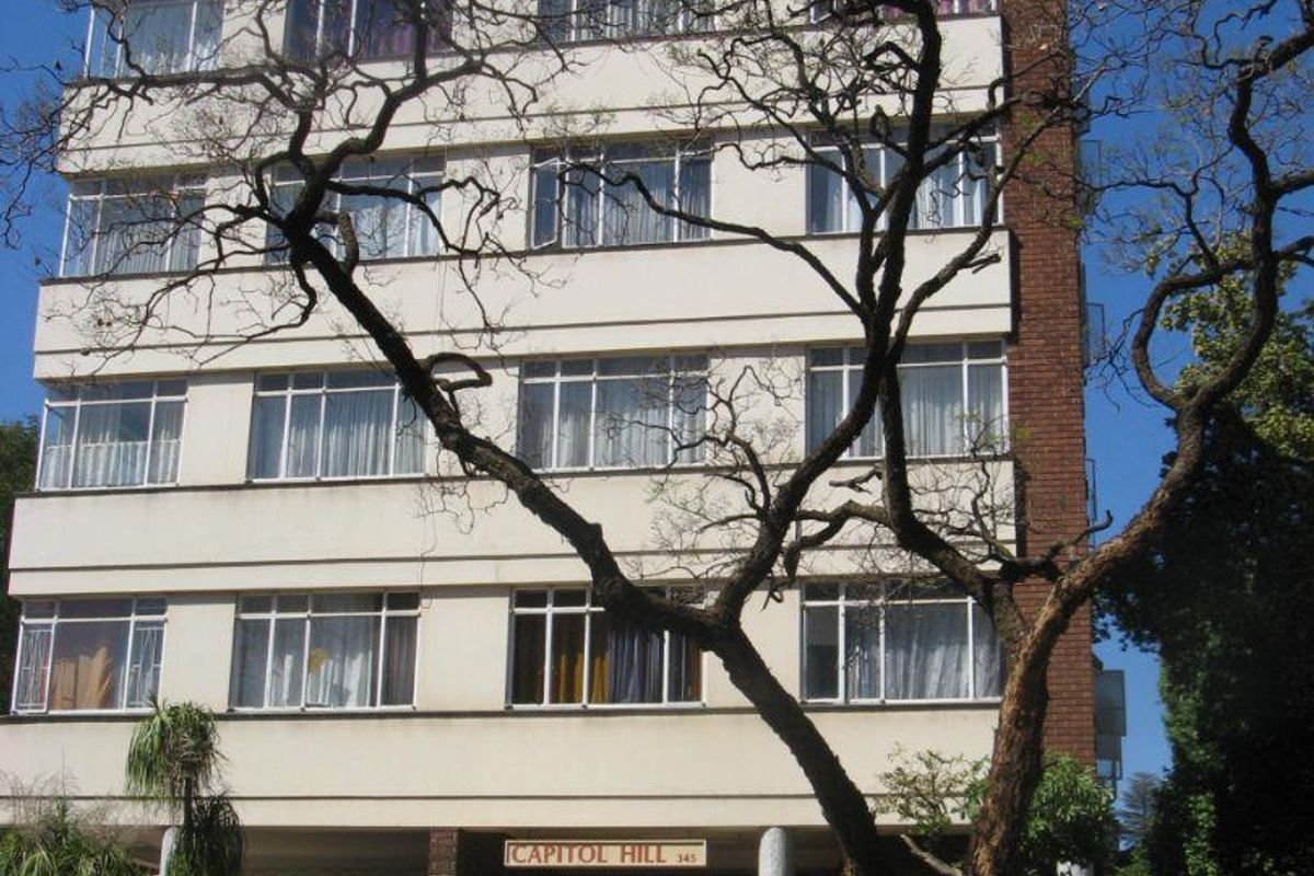 Front elevation of the Capitol Hill apartment building, featuring a multi-story brick and concrete facade with a central entrance and stairs.