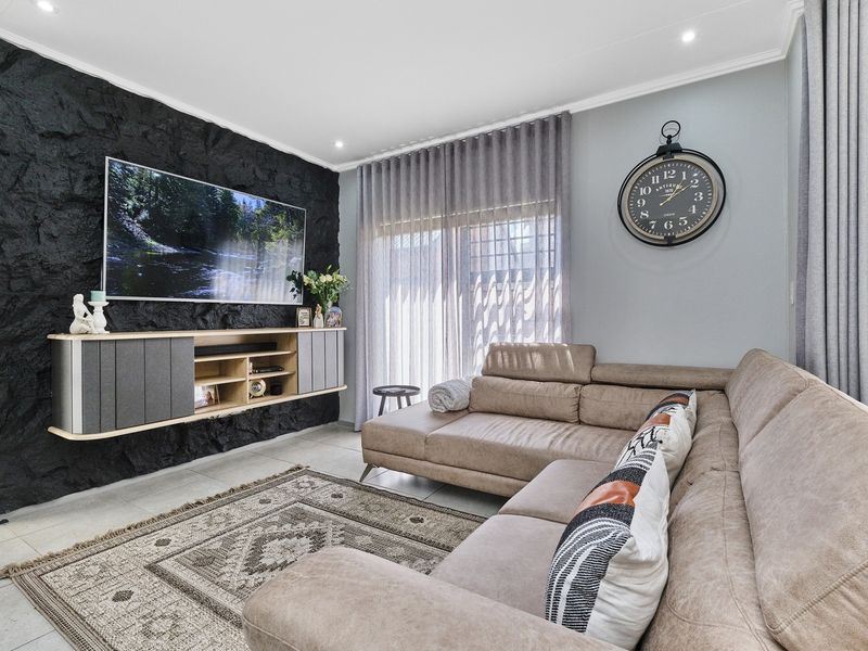 Modern living room featuring a striking black textured stone feature wall, tiled flooring, and large sliding glass doors with elegant curtain treatments.