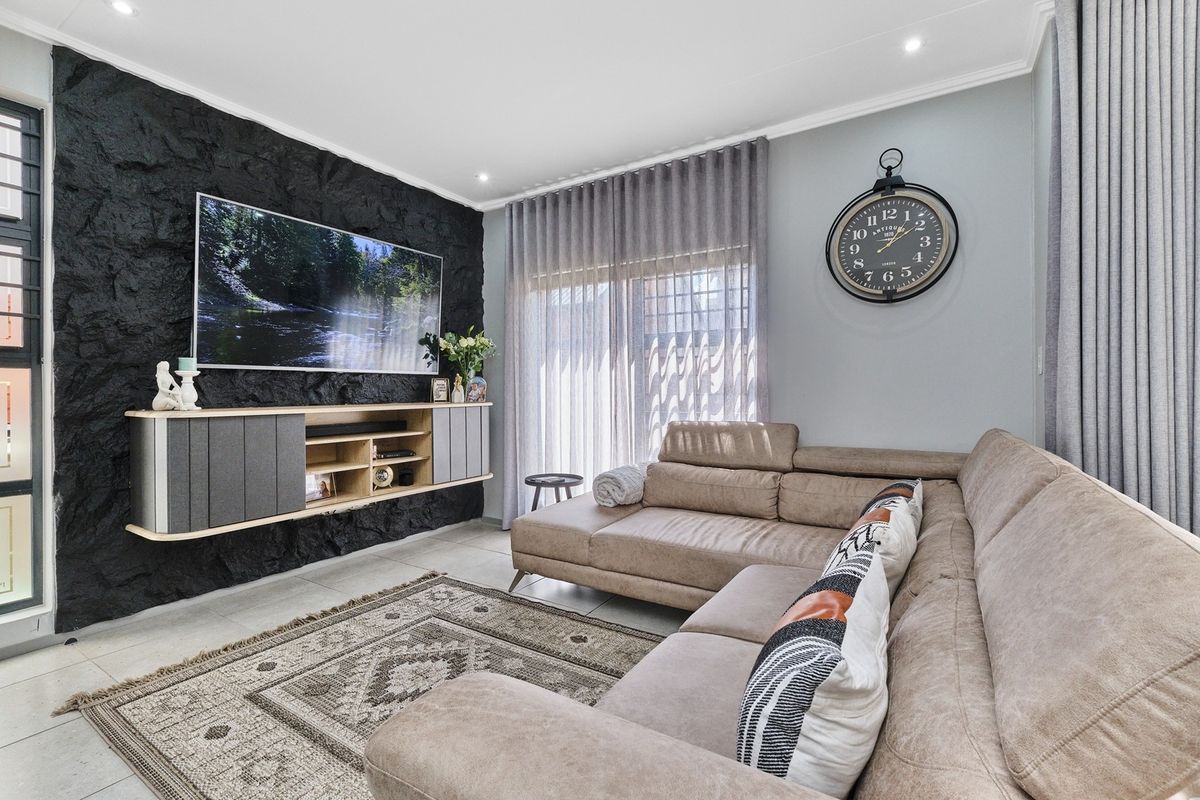 Modern living room featuring a striking black textured stone feature wall, tiled flooring, and large sliding glass doors with elegant curtain treatments.