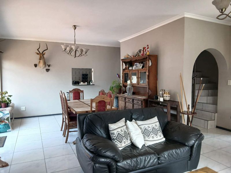 Open plan living and dining area featuring tiled flooring, a decorative archway leading to the staircase, and a convenient serving hatch to the kitchen.