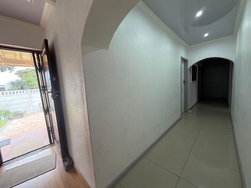 A bright, tiled entrance hall featuring arched architectural details and recessed ceiling lighting, providing a clean and welcoming transition into the home.