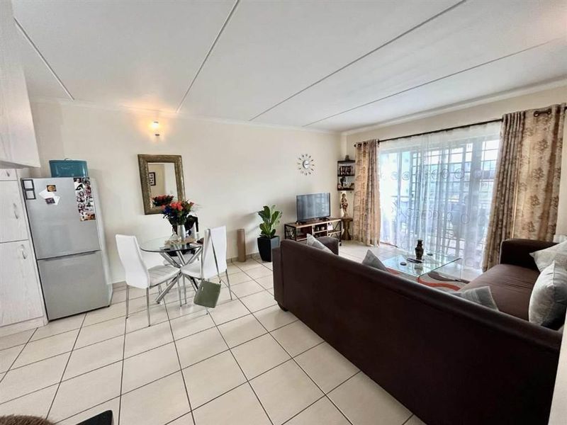 Open-plan living and dining area featuring tiled flooring and a large sliding glass door providing access to the balcony.