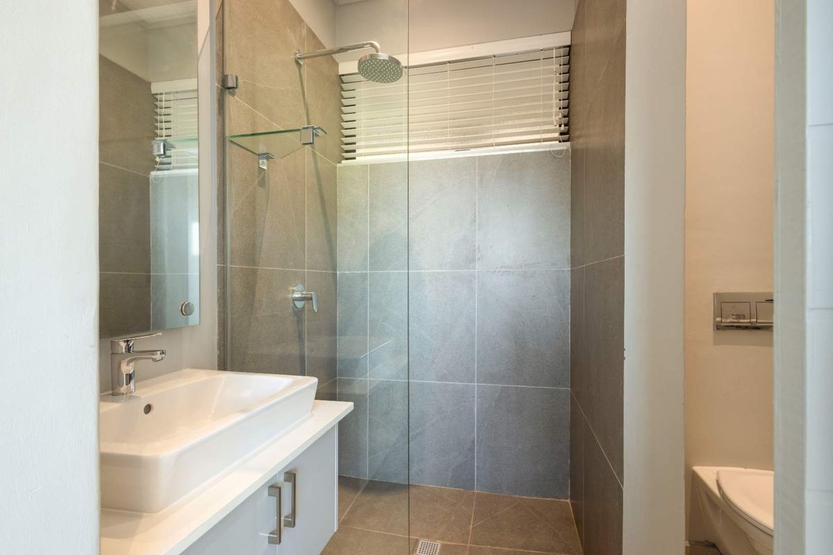 Modern bathroom featuring a glass-enclosed walk-in shower, contemporary vanity with basin, and wall-mounted toilet with concealed cistern.