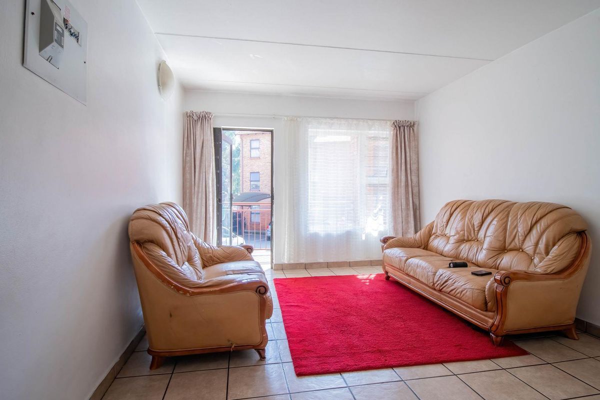A living room featuring tiled flooring and a glass door leading to a balcony, providing natural light and access to outdoor space.