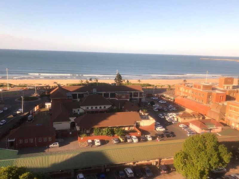Elevated aerial view overlooking the coastline, beach, and surrounding urban infrastructure.