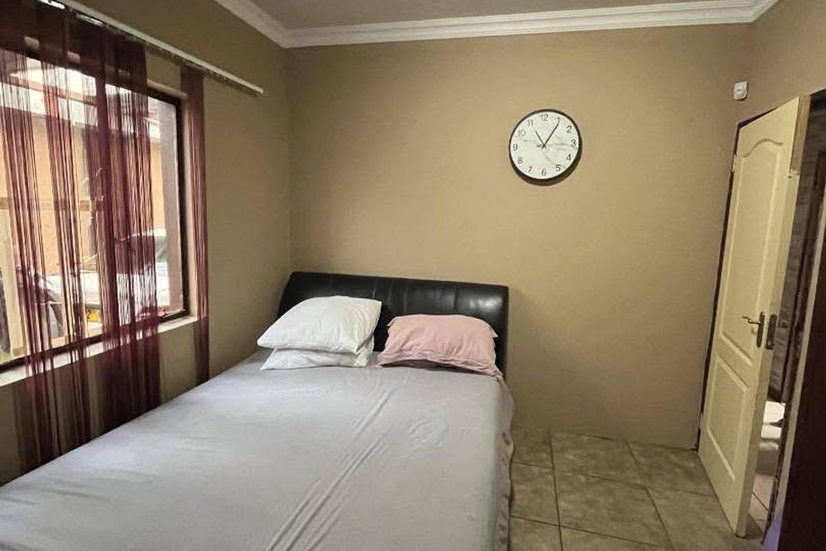 A compact bedroom featuring tiled flooring, neutral wall paint, and a standard window with curtain track.