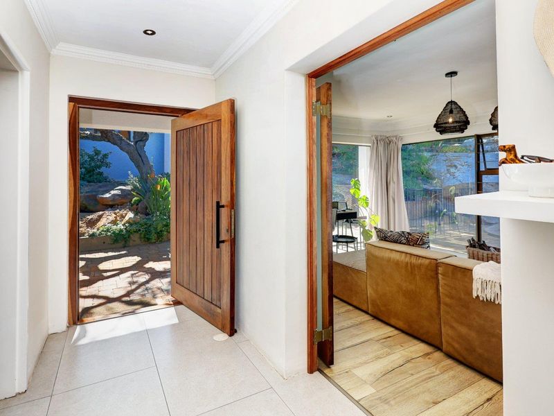 Welcoming entrance hall featuring a solid timber pivot door, neutral tiled flooring, and seamless access to the adjacent living area.