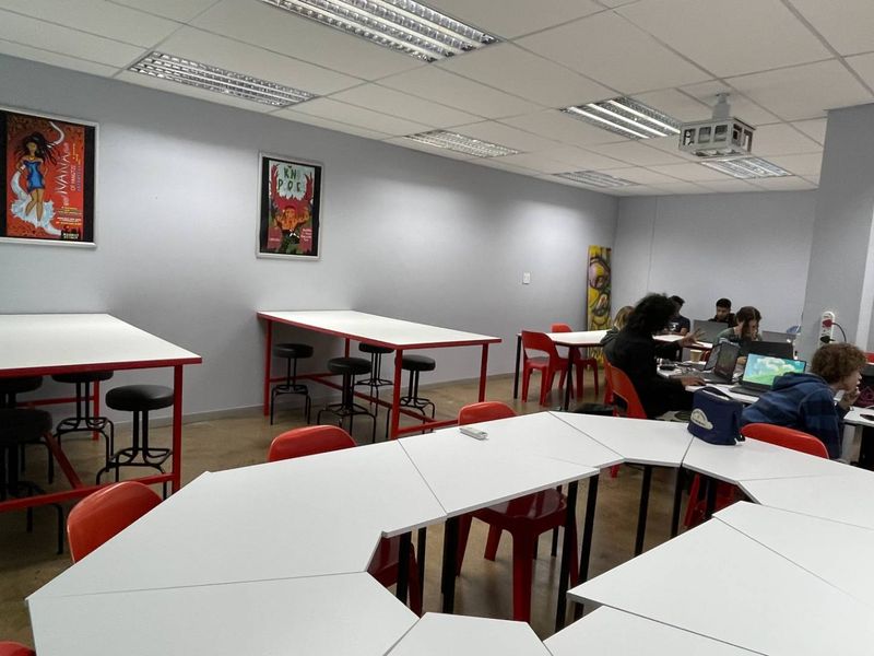 A functional office or collaborative workspace featuring a suspended ceiling with recessed lighting and a ceiling-mounted projector.