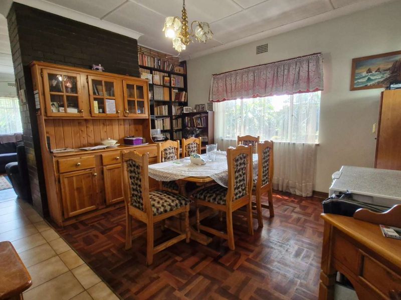 Dining room featuring classic parquet flooring, a brick fireplace, and built-in shelving, offering a traditional layout with natural light.
