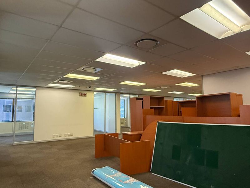 Open plan office space featuring suspended ceilings, recessed lighting, and glass partitioned offices with carpeted flooring.