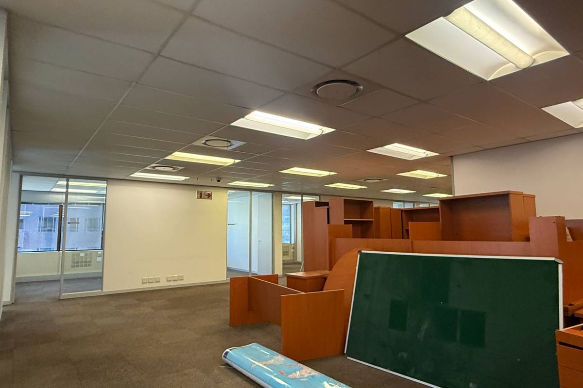 Open plan office space featuring suspended ceilings, recessed lighting, and glass partitioned offices with carpeted flooring.
