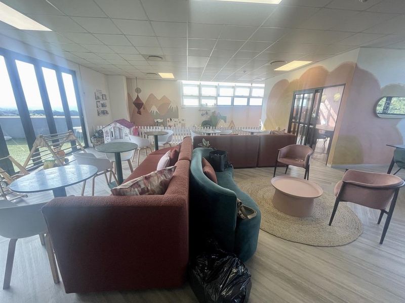 Spacious open-plan area featuring a suspended ceiling, large windows providing natural light, and durable laminate flooring, suitable for a communal or recreational space.