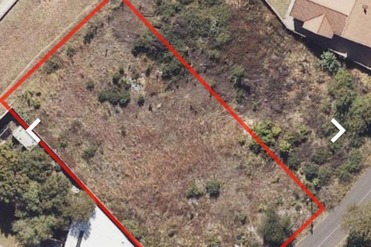 An aerial view of a vacant residential plot of land, showing the property boundaries and surrounding neighborhood context.