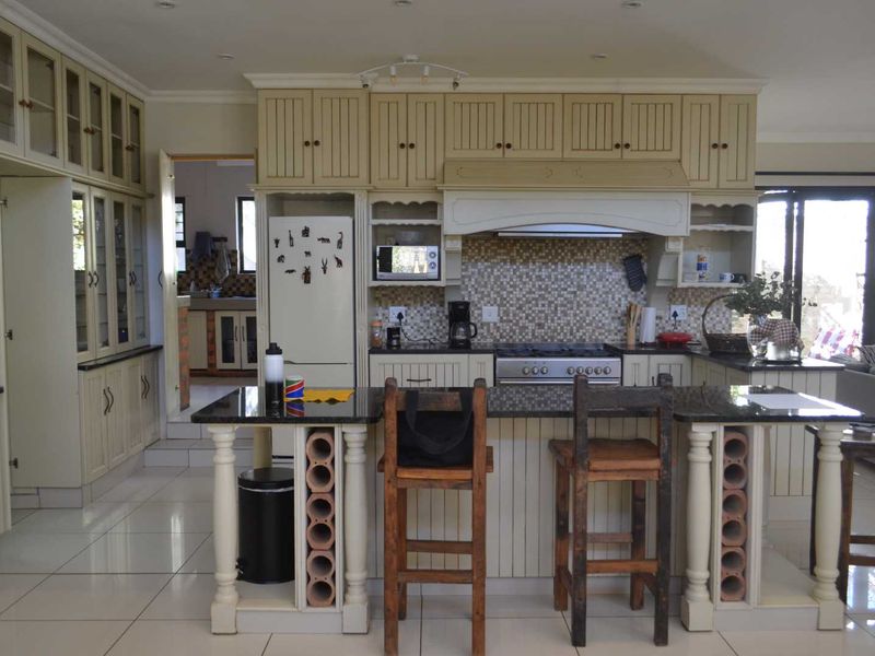 Spacious kitchen featuring cream-colored cabinetry, granite countertops, a central island with integrated wine storage, and a mosaic tile backsplash.