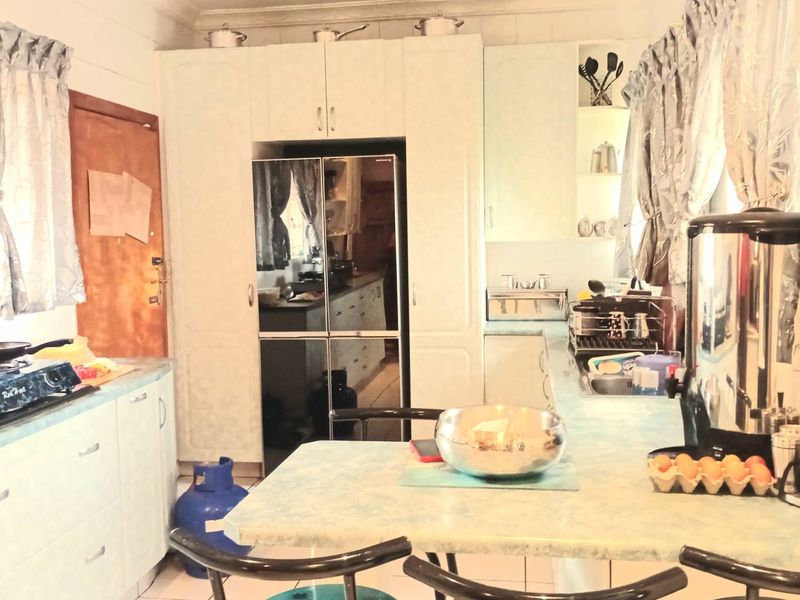 A functional kitchen featuring built-in cabinetry, laminate countertops, and a double sink, offering a practical layout for daily meal preparation.