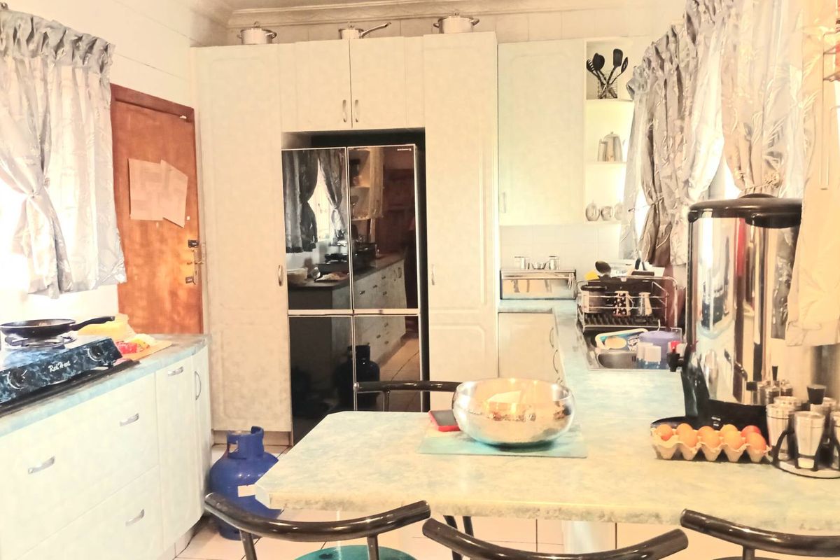 A functional kitchen featuring built-in cabinetry, laminate countertops, and a double sink, offering a practical layout for daily meal preparation.