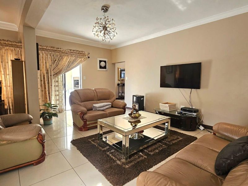 Spacious living room featuring neutral wall tones, polished tiled flooring, decorative ceiling lighting, and direct access to an outdoor area via sliding glass doors.