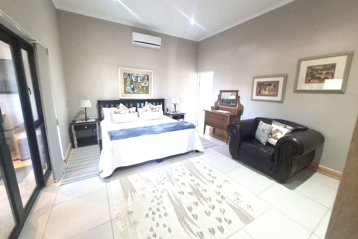 Spacious bedroom featuring tiled flooring, recessed downlighting, and a wall-mounted air conditioning unit with direct access to an outdoor area.