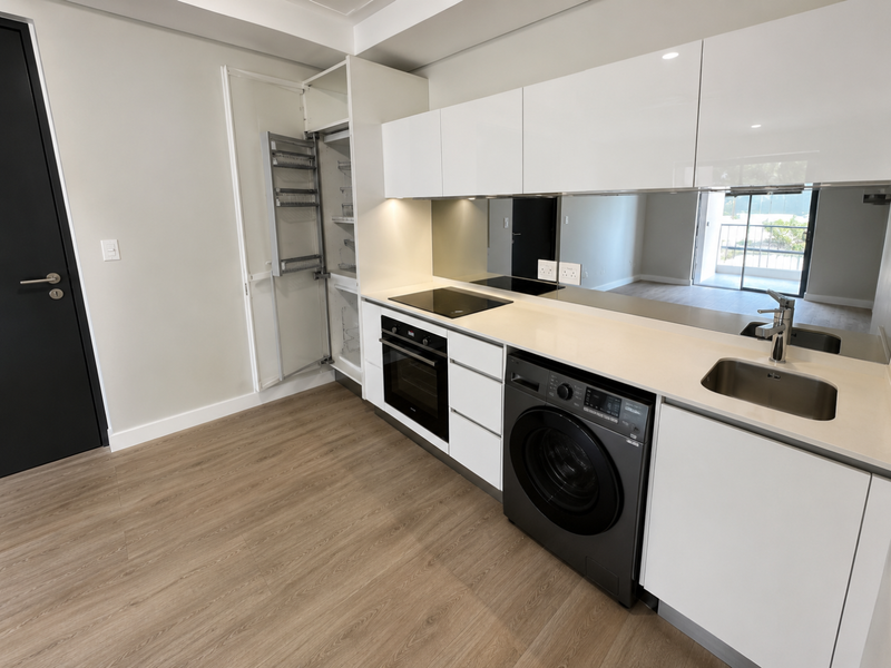 Modern kitchen featuring white gloss cabinetry, integrated pull-out pantry, built-in oven, electric hob, stainless steel sink, and a sleek mirrored splashback.
