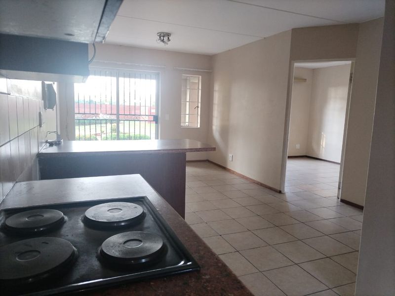 Open-plan kitchen and living area featuring tiled flooring, a breakfast bar, and direct access to an outdoor space through a sliding glass door.