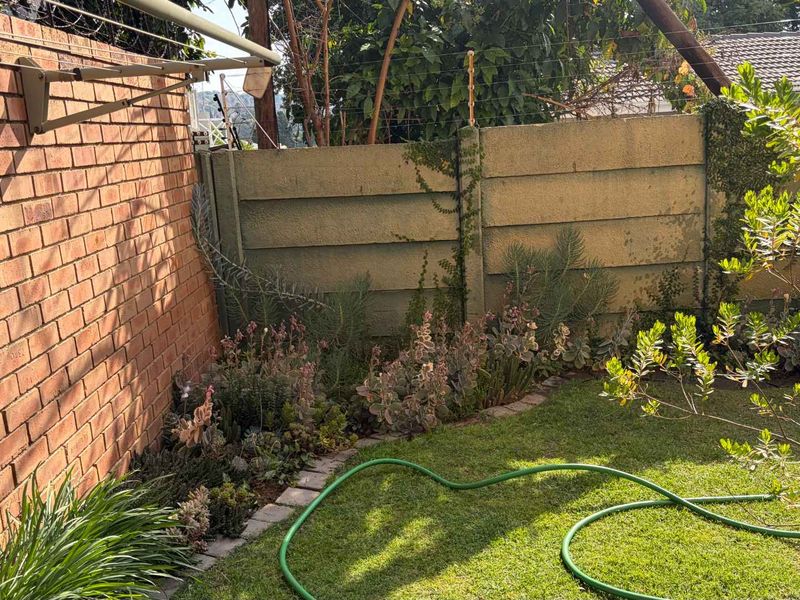 A private rear garden area featuring a brick boundary wall, precast concrete fencing with electric security wires, and a wall-mounted washing line.