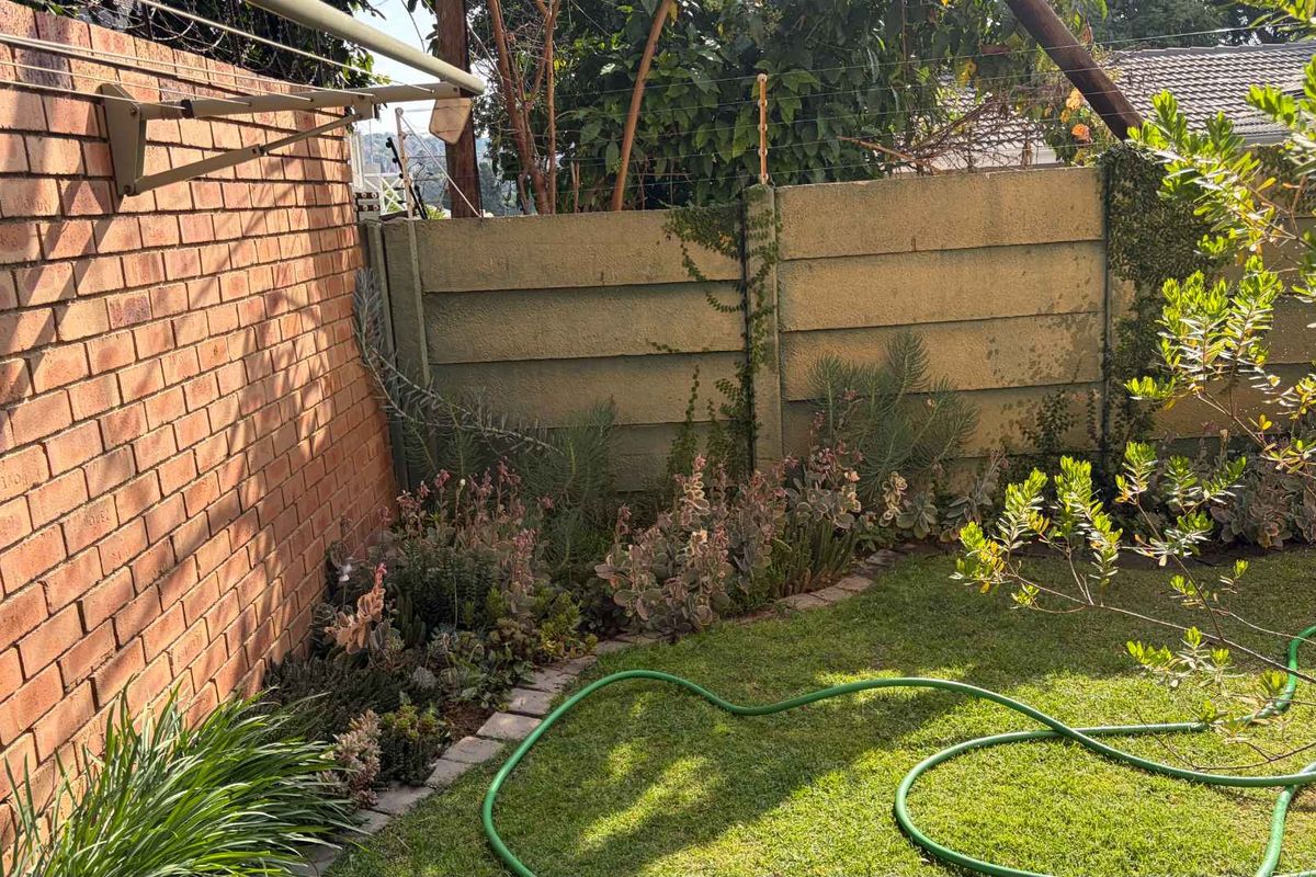 A private rear garden area featuring a brick boundary wall, precast concrete fencing with electric security wires, and a wall-mounted washing line.