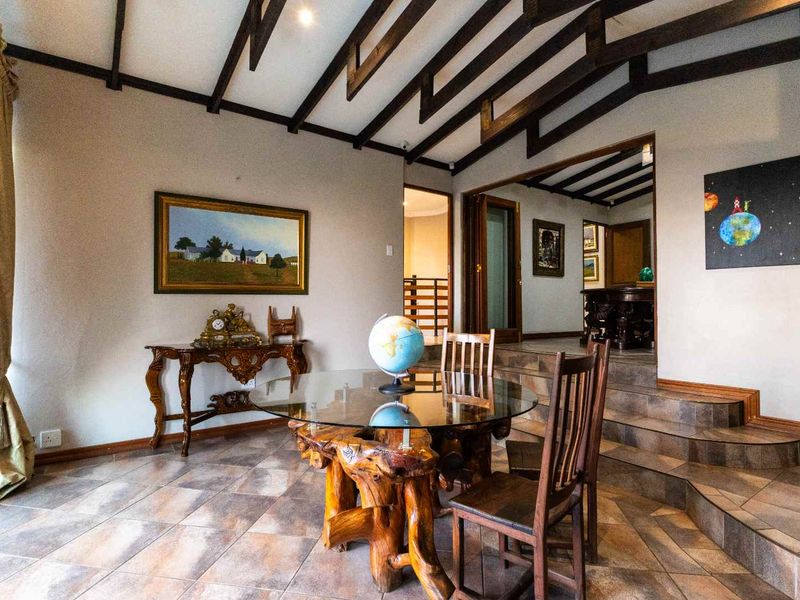 Dining area featuring exposed timber ceiling beams, tiled flooring, and a split-level layout with tiled stairs leading to an adjacent room.