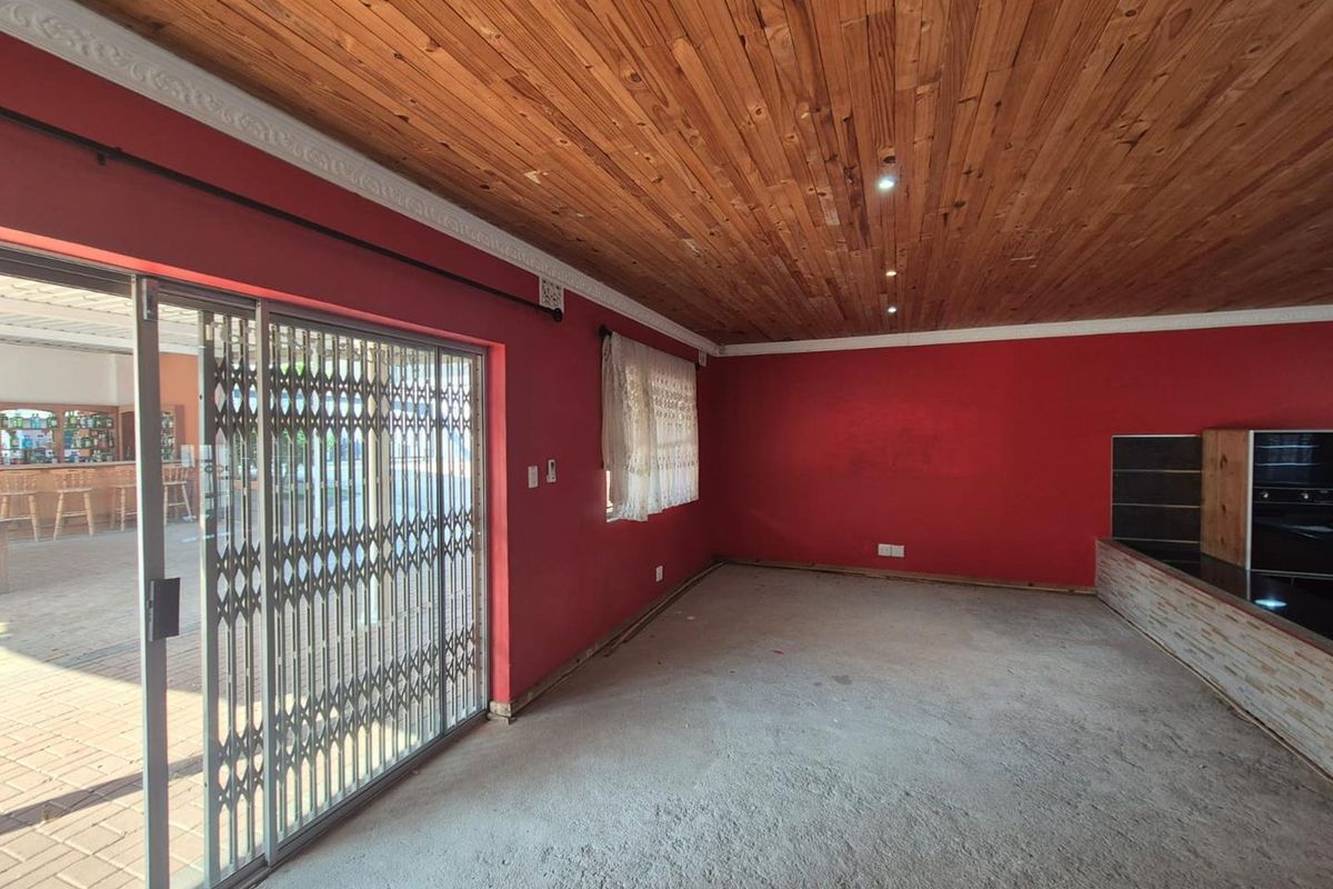An empty living room featuring a timber ceiling, built-in fireplace, and sliding door access to an outdoor patio area.