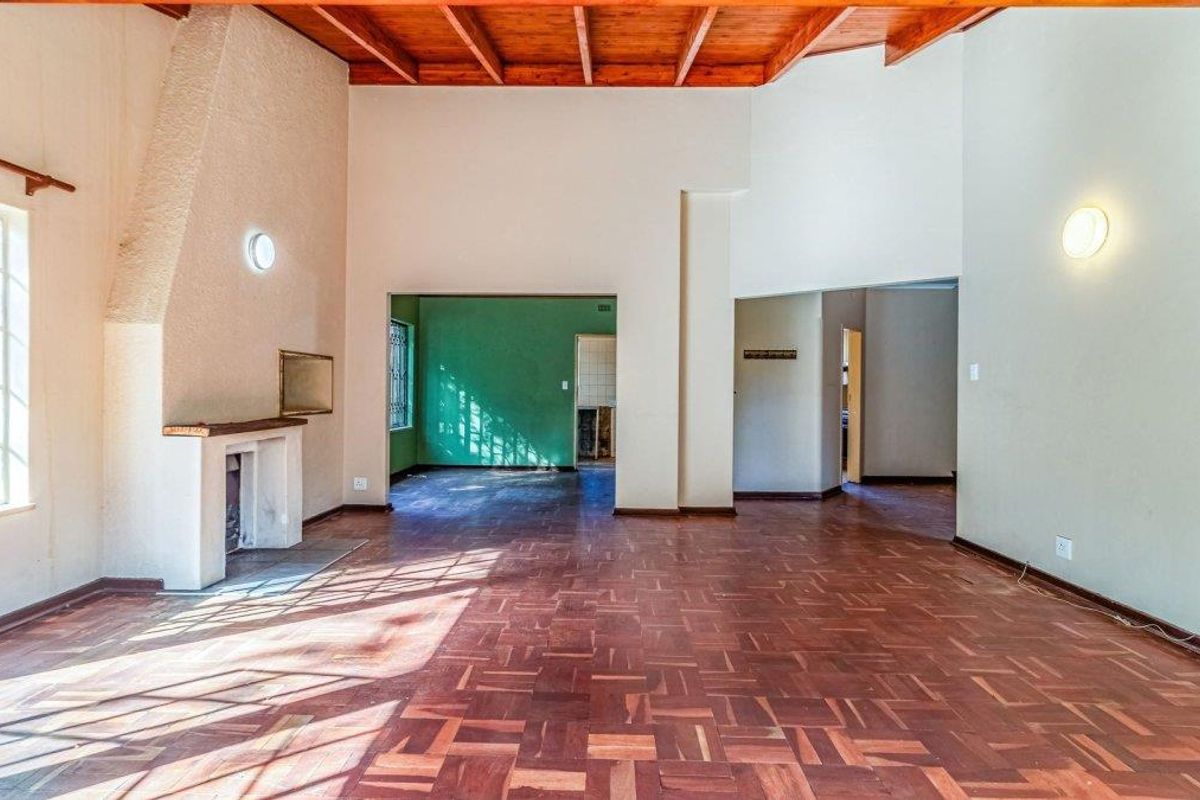 Spacious living room featuring high exposed timber beam ceilings, classic parquet flooring, and a built-in fireplace, offering a bright and open layout.