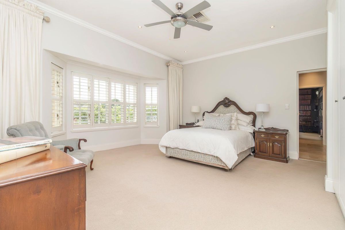 Spacious bedroom featuring a bay window with plantation shutters, crown molding, recessed lighting, and a ceiling fan.