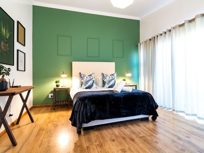 A well-maintained bedroom featuring laminate flooring, decorative wall molding, crown molding, and a large sliding glass door providing natural light.