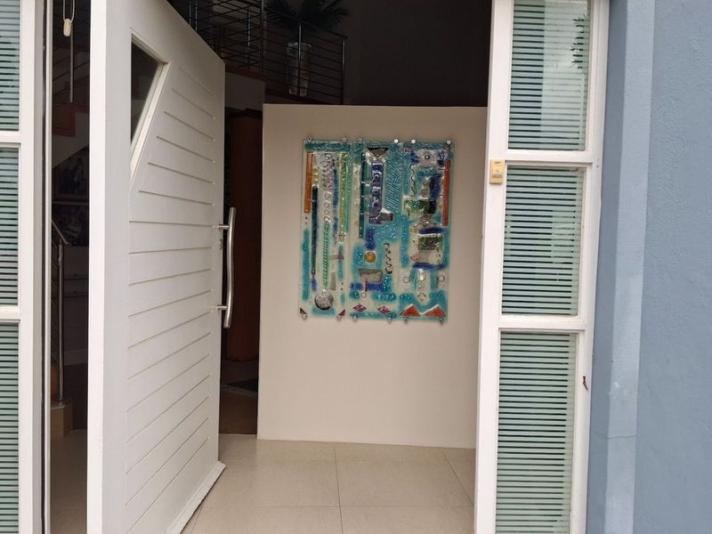 A bright and welcoming entrance featuring a large modern pivot door with side light windows and clean tiled flooring.