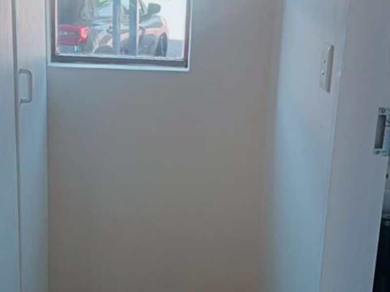 A compact, empty hallway featuring tiled flooring and a built-in storage cupboard, providing a clean and functional transition space within the apartment.