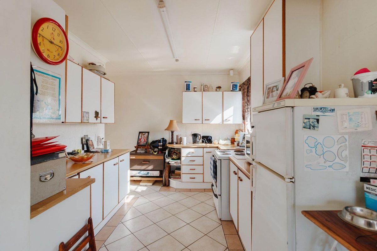 A functional kitchen featuring white cabinetry, laminate countertops, and tiled flooring, offering a dated layout ready for modern updates and renovation.