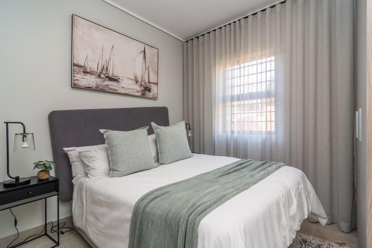 A well-maintained bedroom featuring neutral tones, floor-to-ceiling curtains, and a built-in wardrobe, offering a comfortable and modern living space.