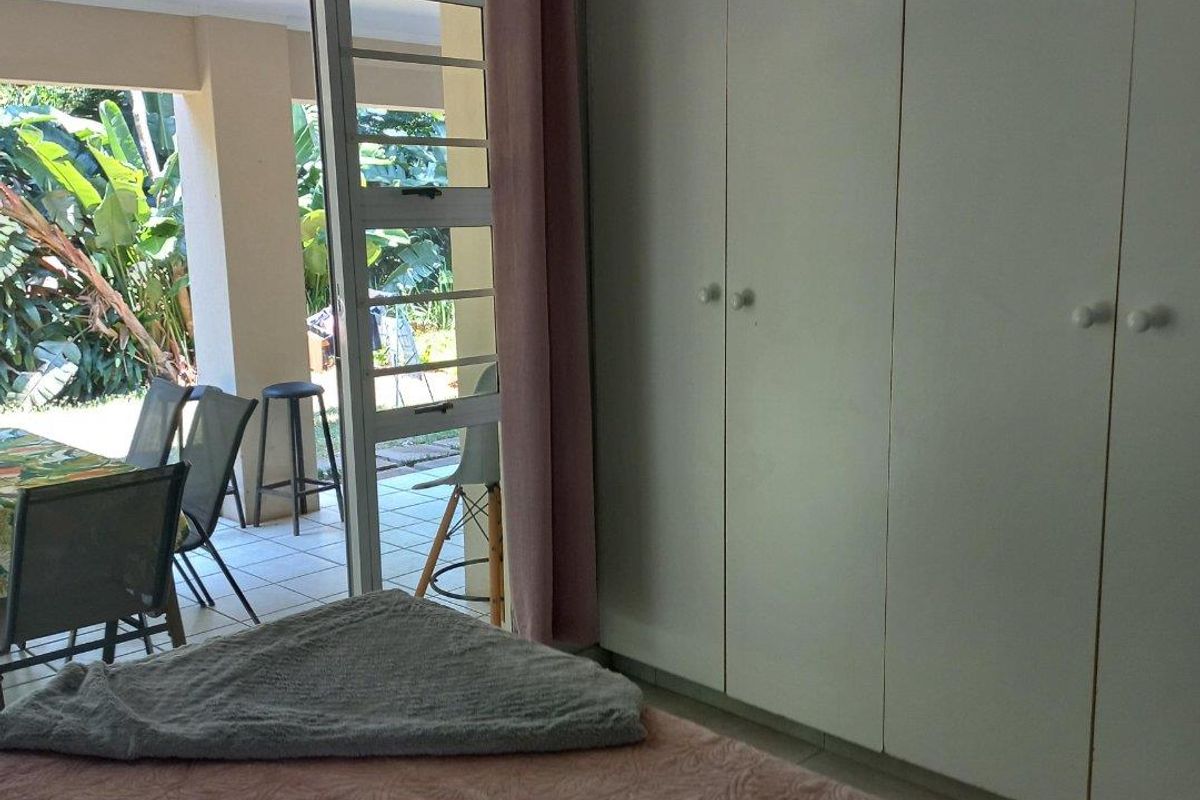 Bedroom featuring built-in wardrobes and direct access to a covered patio area through a glass sliding door.