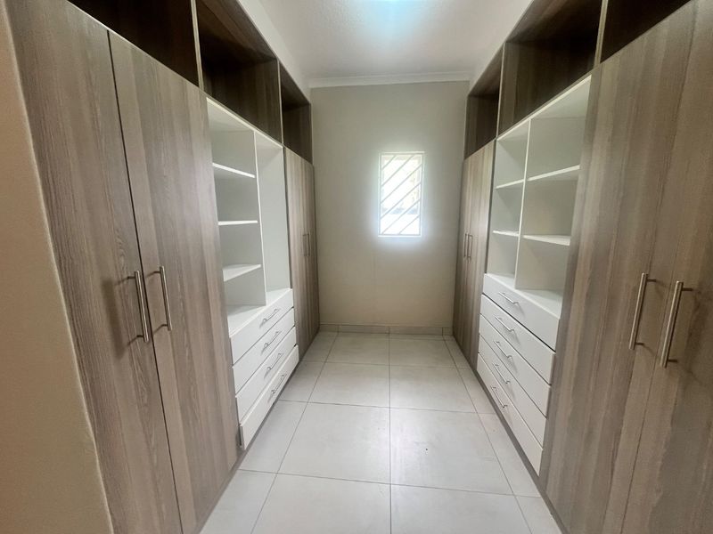 A well-maintained walk-in closet featuring extensive built-in cabinetry with ample shelving and drawer storage, finished with modern tiled flooring.