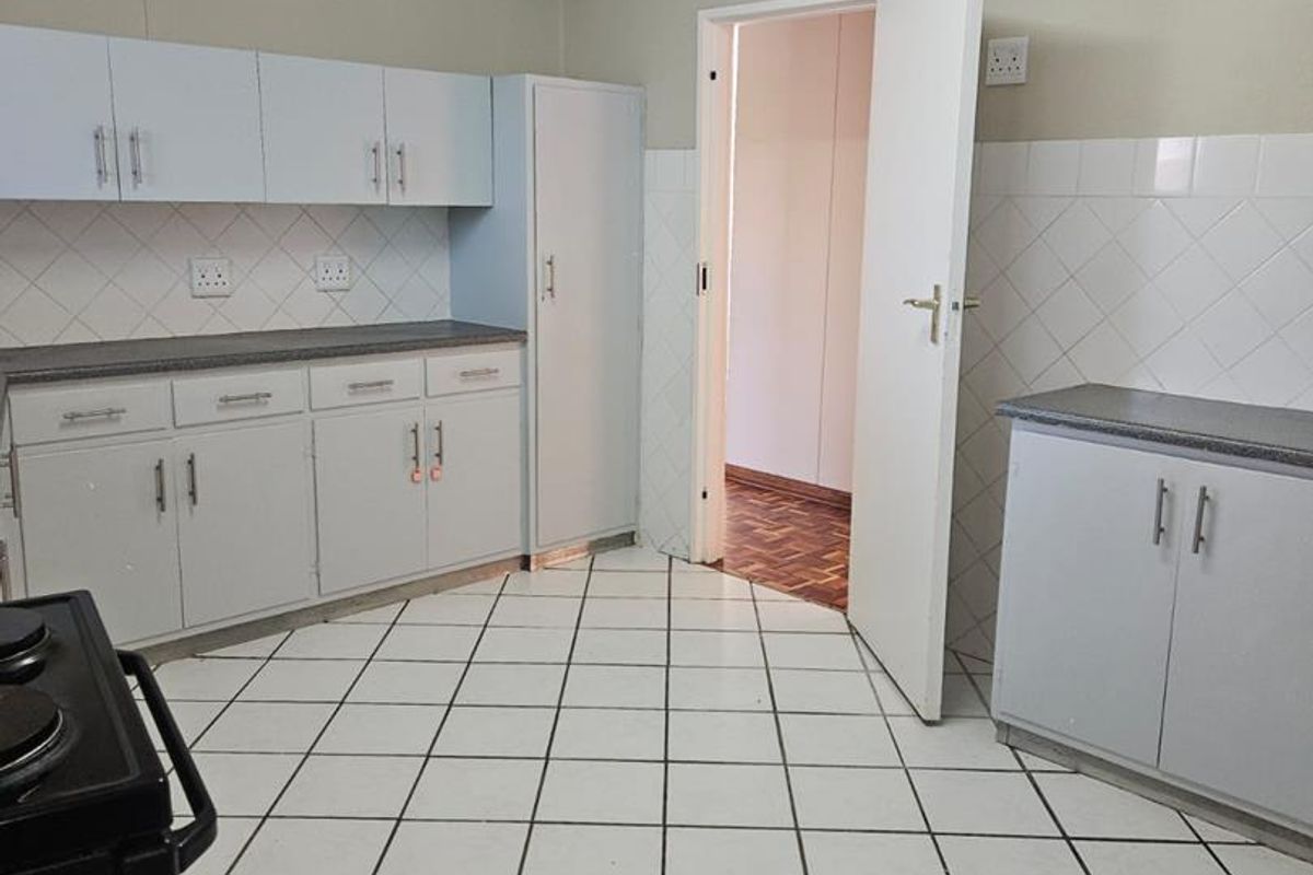 A functional kitchen featuring white built-in cabinetry, laminate countertops, tiled backsplash, and ceramic floor tiles, offering a clean and practical layout.