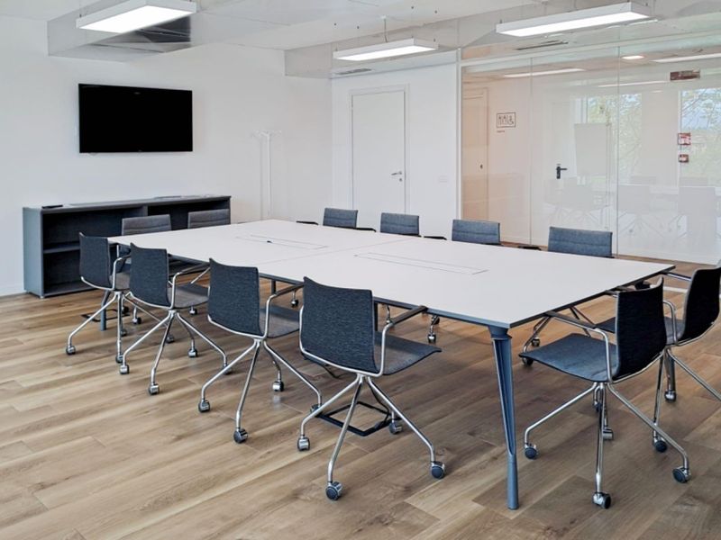Modern professional office meeting room featuring high-quality laminate flooring, glass partition walls, and integrated lighting fixtures.