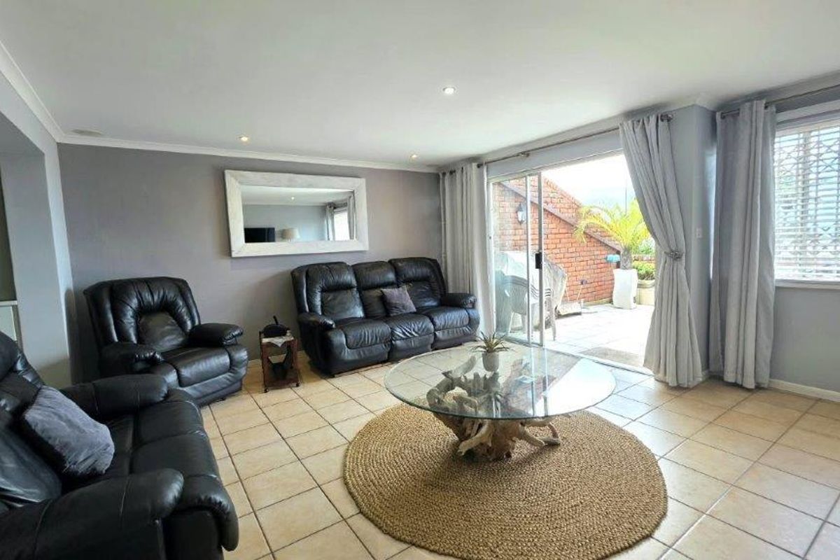 Spacious living room featuring neutral tiled flooring, recessed lighting, and large sliding glass doors providing direct access to an outdoor patio area.