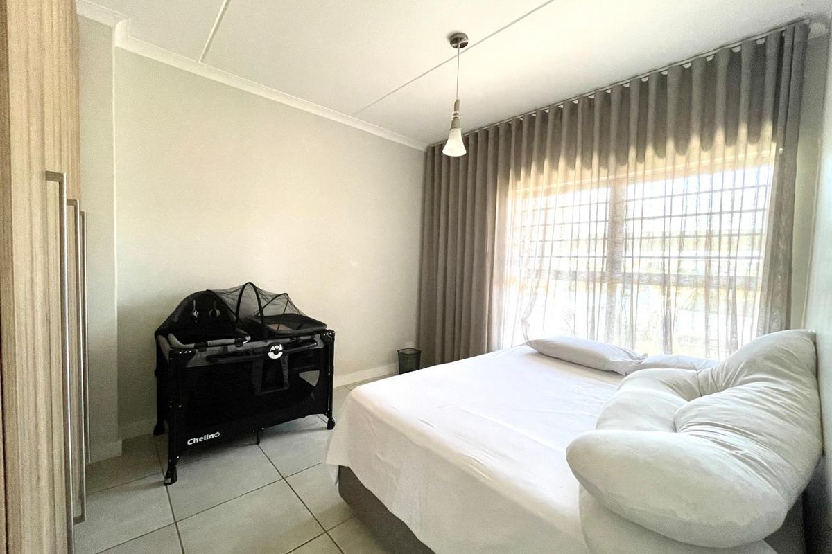 A well-lit bedroom featuring neutral tiled flooring, built-in cabinetry, and floor-to-ceiling curtains.
