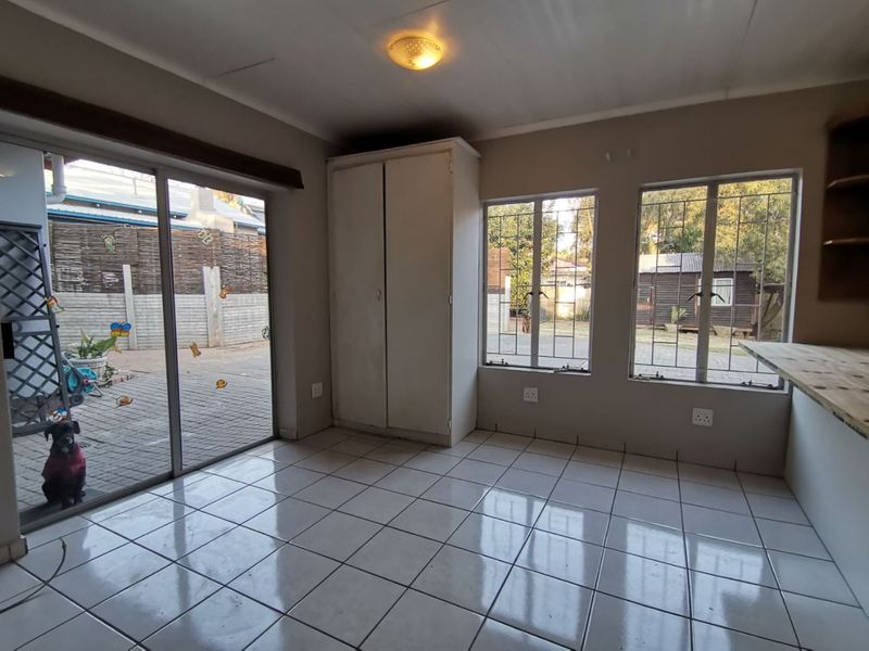 A bright, tiled living area featuring a built-in cupboard, large sliding doors leading to the patio, and security-fitted windows.