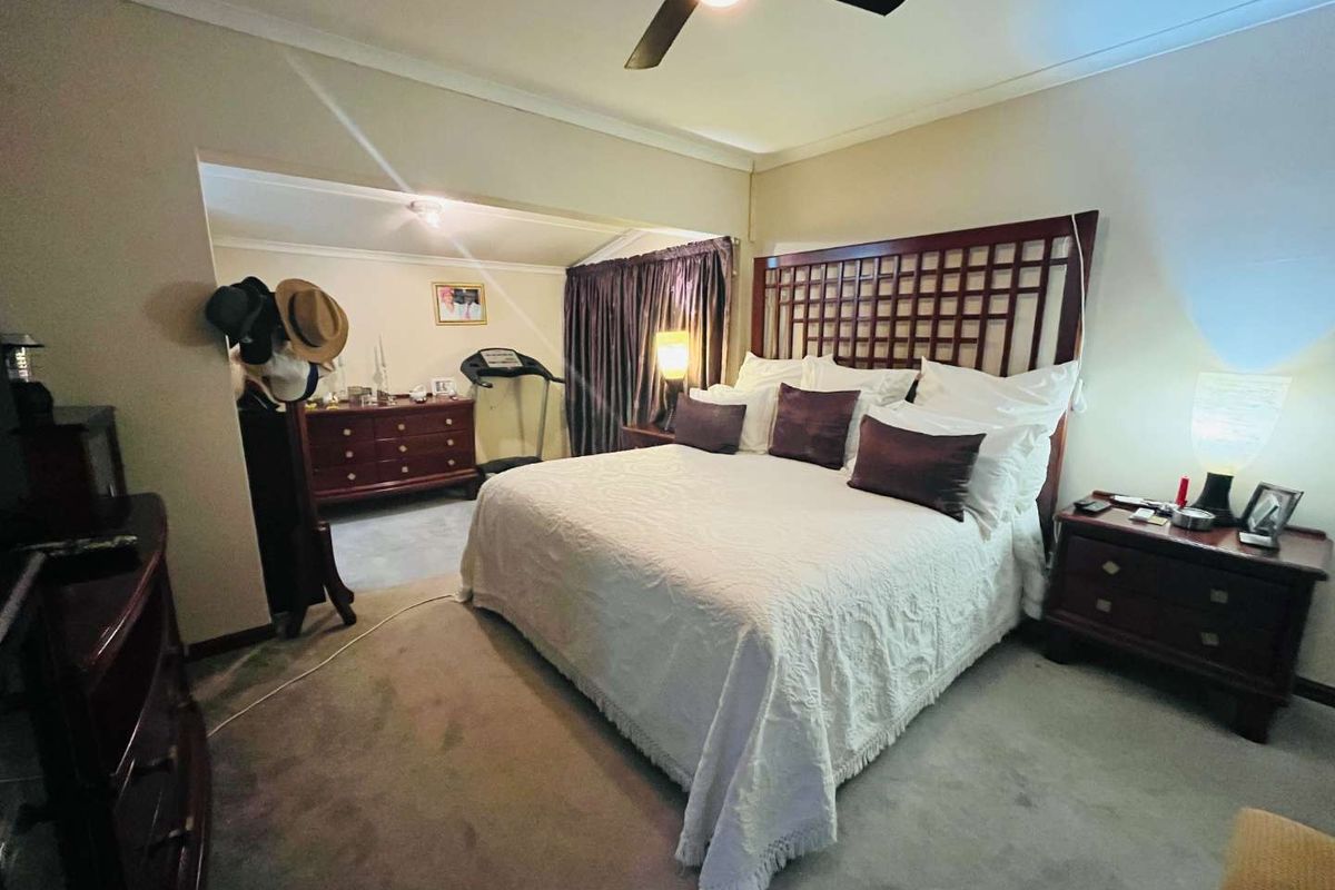 Spacious bedroom featuring a ceiling fan, neutral wall tones, and an adjoining alcove area suitable for a dressing space or home gym setup.