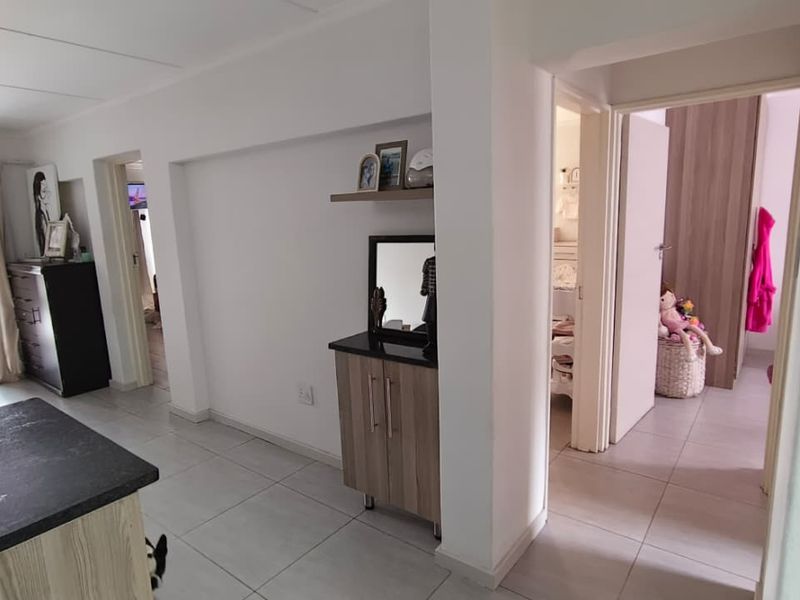 Open plan living area featuring tiled flooring and neutral walls, providing access to adjacent rooms and a patio area.
