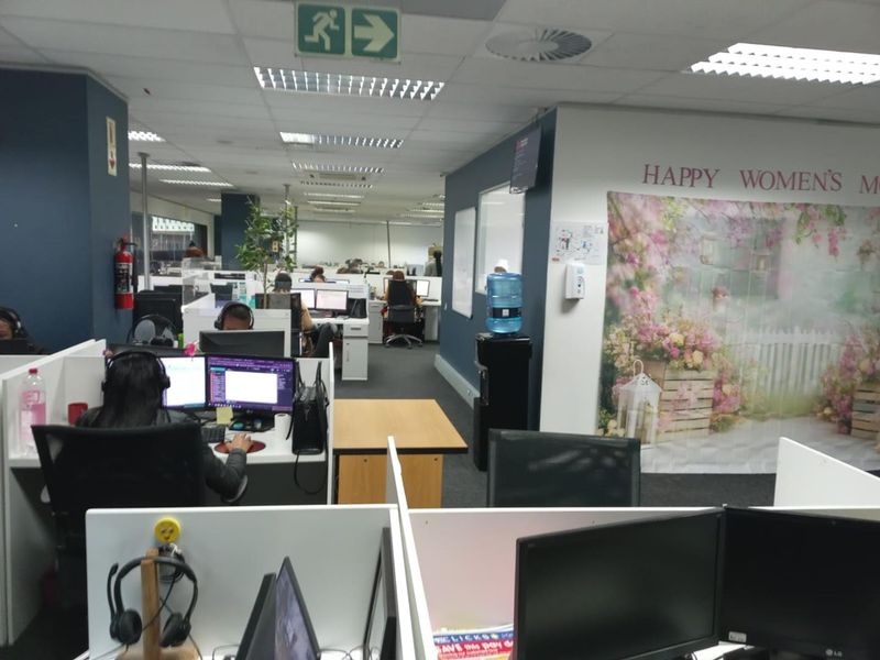 A functional open-plan office space featuring modular workstations, suspended ceilings with recessed lighting, and carpeted flooring.