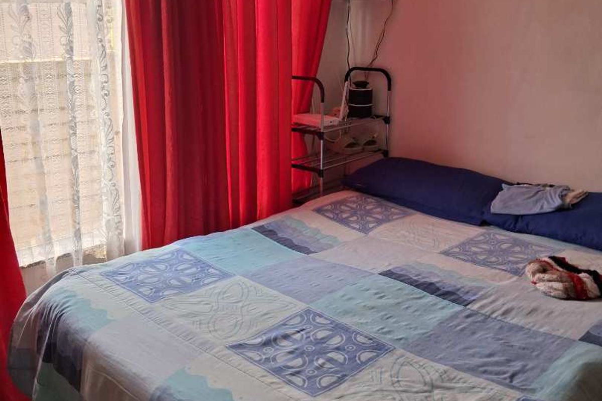 A bedroom featuring tiled flooring and a window with curtains.