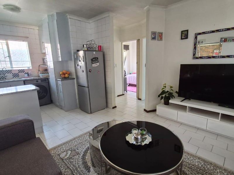 Open-plan living area featuring a functional kitchen with tiled finishes and direct access to adjacent rooms.