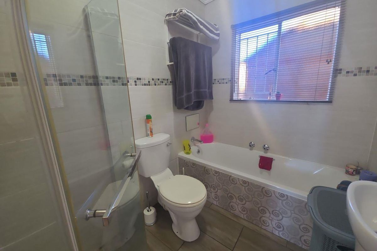 A functional bathroom featuring a bathtub, separate shower enclosure, toilet, and basin with tiled finishes throughout.