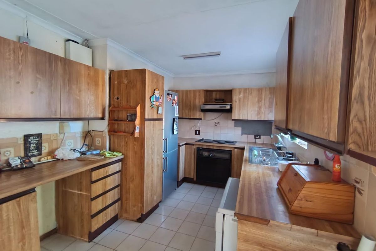 A functional kitchen featuring wood-look cabinetry, built-in oven, extractor fan, and tiled flooring, offering a practical layout for daily meal preparation.