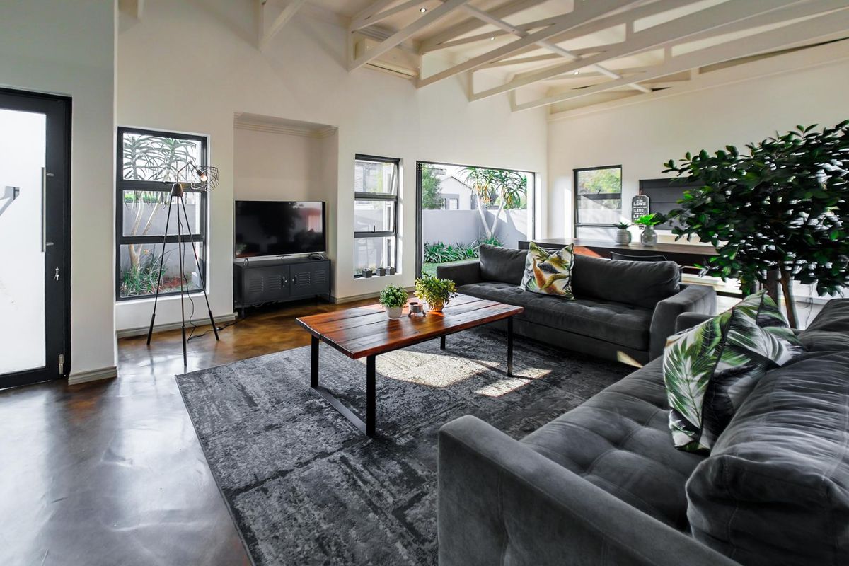 Spacious living area featuring high vaulted ceilings with exposed timber trusses, polished concrete floors, and large windows providing ample natural light.